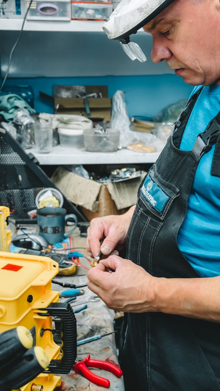 A technician repairs machinery parts in a busy workshop, showcasing precision and detail.