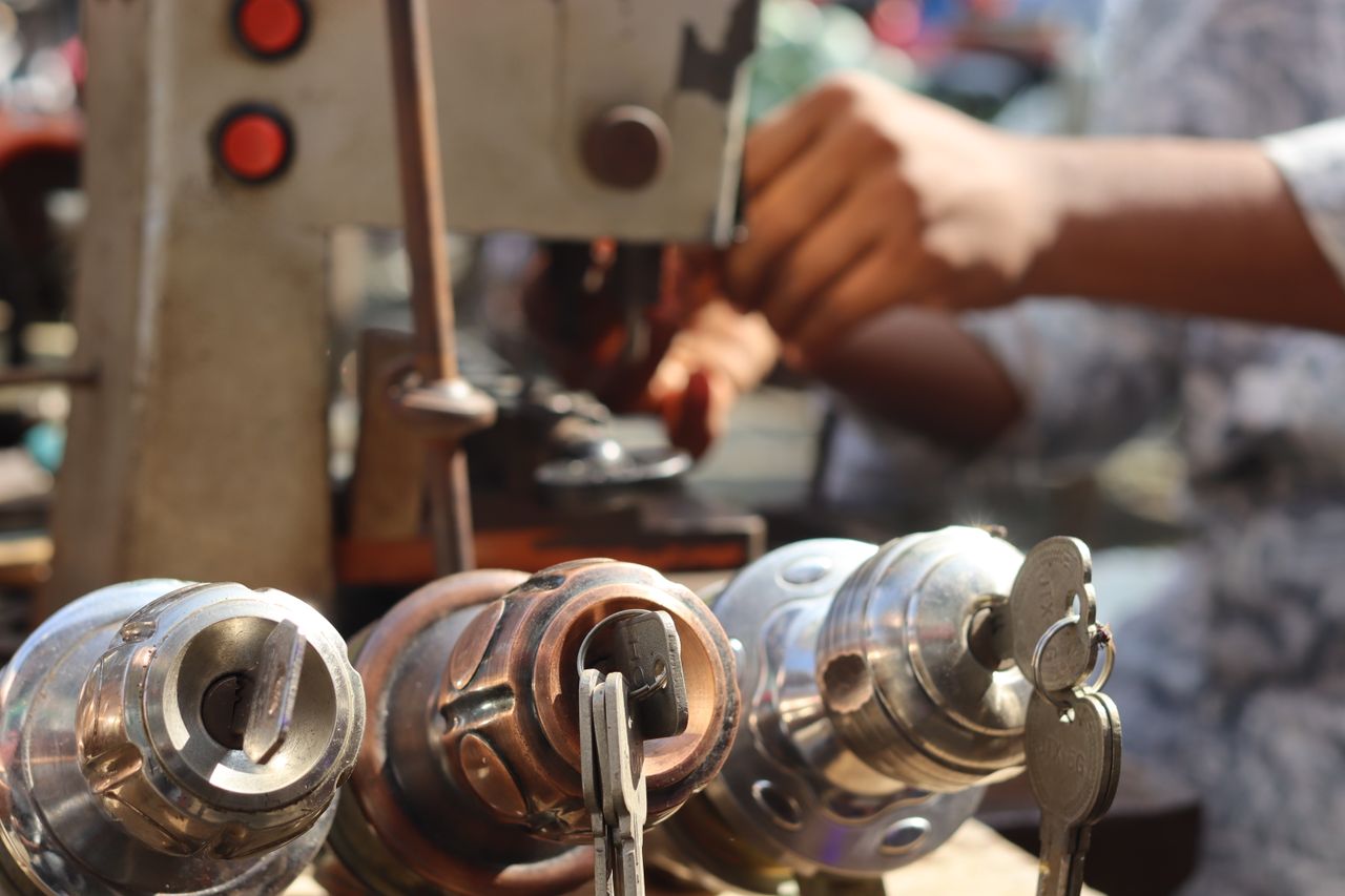 team-01 Close-up image of locksmith tools and hands working with a key machine outdoors.