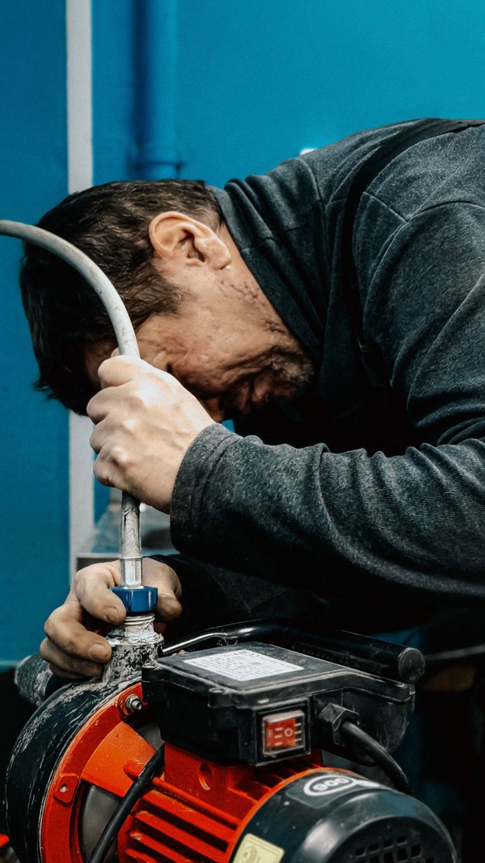 embark A technician concentrates on adjusting a water pump indoors.