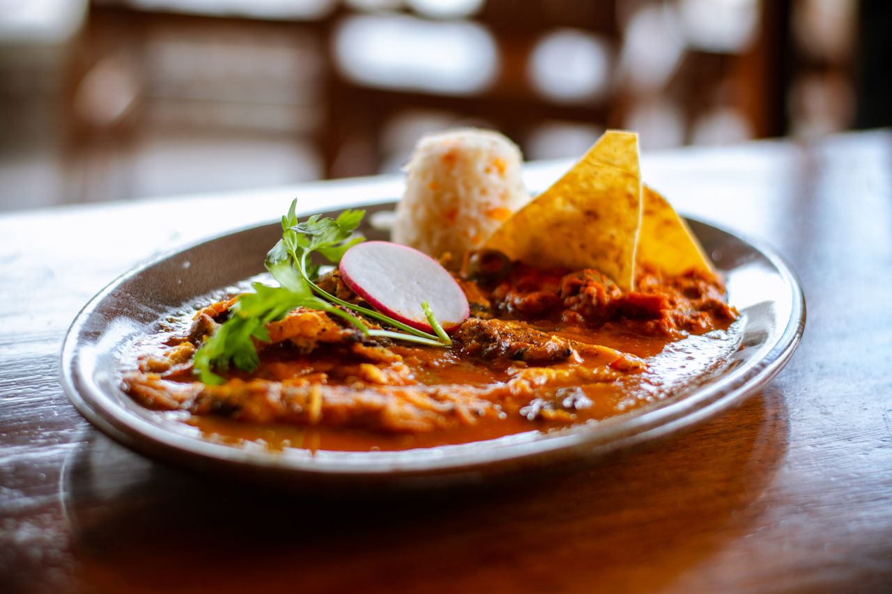 our-story-01 Close-up of a Mexican meal featuring rice, tortilla chips, and spicy sauce, perfect for cuisine lovers.
