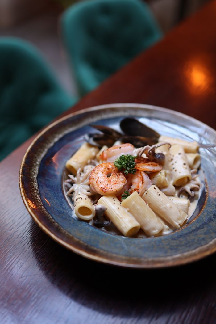 services-03 Pasta dish with shrimp and mushroom sauce served on a rustic plate.