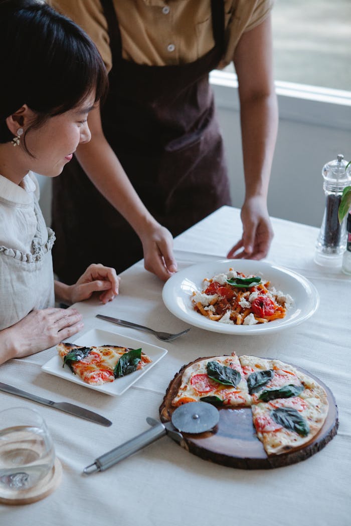 about-07 A woman enjoys Italian cuisine with pizza and pasta at a cozy restaurant.